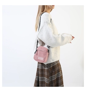 Détail du petit sac bandoulière en velours côtelé rose avec écusson Fashion et sangle