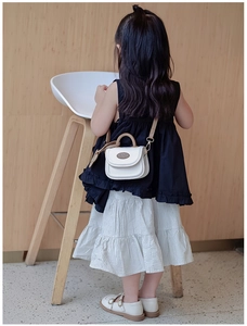 Vista posteriore di un bambino con una borsa mini bianca e marrone su pareti di legno