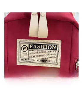 Détail du sac à dos en toile rouge avec étiquette vintage et double fermeture éclair
