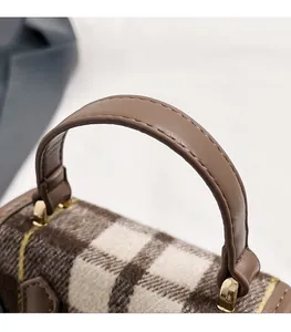 Détail du sac en tweed à carreaux avec poignée en cuir marron et attaches dorées