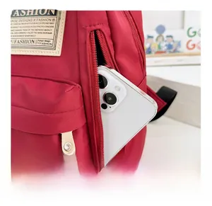 Gros plan de la poche avant zippée d'un sac à dos enfant rouge contenant un téléphone