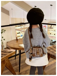 Detail view of a quilted brown and beige bucket bag with a cute rabbit plush pendant