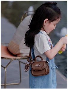 Dettaglio mini borsa a tracolla marrone per bambini con ciondolo a orso e logo