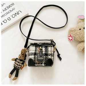 Detail of tweed bucket bag with black leather trim, fashion tag and cute rabbit charm
