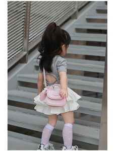 Vista posteriore di una bambina con mini borsa rosa, top grigio e gonna a balze bianca