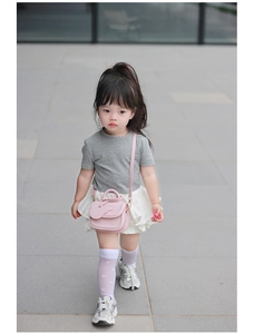 Bambina che indossa una mini borsa a tracolla rosa in pelle PU con ciondolo a cuore