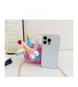 Sac à main en peluche rose pour filles avec poignée perle à côté d'un smartphone pour taille