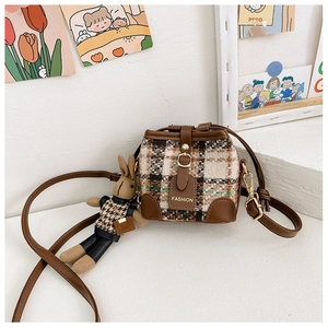 Detail of plaid tweed bucket bag featuring a brown leather strap and a cute bunny charm