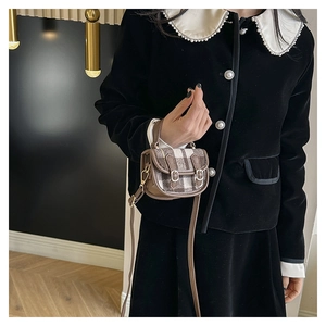Détail du mini sac à main vintage à carreaux avec garniture en cuir porté par un modèle