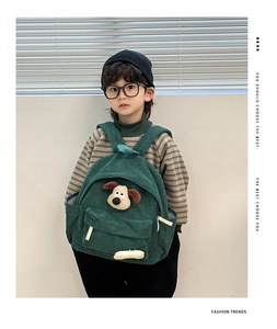 Detail of green corduroy kids backpack featuring a 3D cartoon dog and textured fabric
