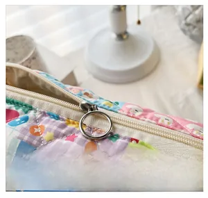 Close-up of a floral quilted bag showing a smooth silver metal zipper and cute cartoon prints