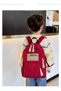 Détail du sac à dos en toile rouge avec étiquette beige et poches zippées pratiques