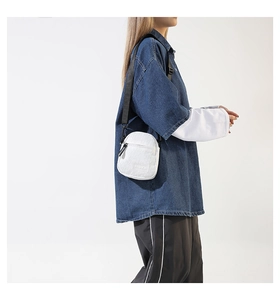 Détail d'un mini sac bandoulière blanc en toile avec logo et sangle réglable noire
