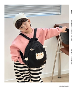 Toddler modeling a black lightweight canvas backpack with cute cartoon sheep and 3D ears