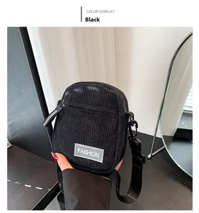 Détail de la texture du velours côtelé noir et du logo FASHION sur le sac bandoulière