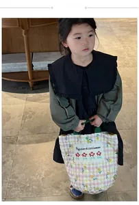 Gros plan du sac à main matelassé beige brodé de fleurs et robe verte à manches longues