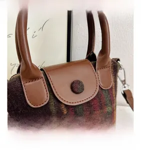 Dettaglio della trama del tessuto a scacchi e del manico in pelle della borsa da bambina