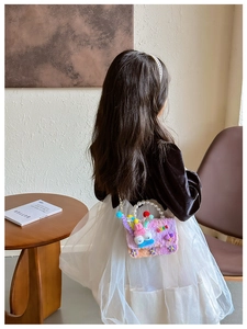 Détail d'un sac bandoulière en peluche pour fille avec poignée en perles et breloques