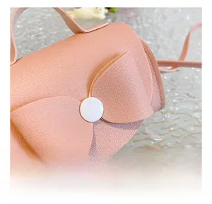 Detail showing the pink litchi grain leather texture and large bow on the kids' mini bag