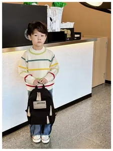 Détail d'un sac à dos noir léger pour enfants avec écusson et fermetures éclair beige