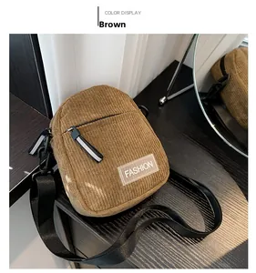 Détail de la sacoche en velours côtelé marron avec logo Fashion sur table en bois