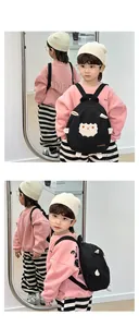 Toddler modeling black canvas sheep backpack showing front and side views in a mirror
