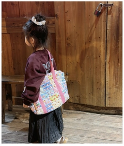 Detail of floral quilted crossbody bag showing colorful cartoon patterns on a child