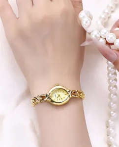 Detail view of elegant gold-tone oval quartz watch with intricate hollow metal bracelet