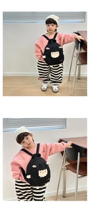 Toddler wearing a black canvas sheep backpack with Toomesio lettering in a studio
