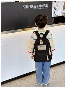 Détail d'un sac à dos noir pour enfant en toile avec des fermetures éclair crème