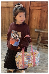Detail of a floral quilted crossbody bag paired with a burgundy chipmunk graphic sweatshirt