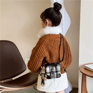 Girl wearing a stylish tweed quilted bucket bag with a cute plush rabbit pendant charm