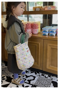 Détail d'un sac cabas en coton matelassé à fleurs avec anses vertes pour filles