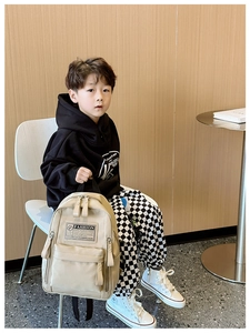 Détail du sac à dos enfant en toile beige avec écusson Fashion et poches latérales