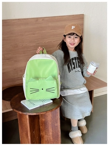 Kid back view showing cartoon cat backpack with 3D ears in green and white colors