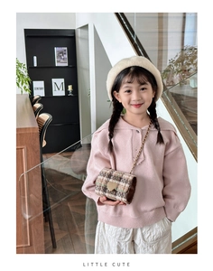 Girl wearing brown plaid crossbody bag with metal heart and golden chain strap