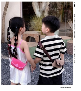 Toddlers wearing pink and beige mini PU leather crossbody bags in an outdoor setting