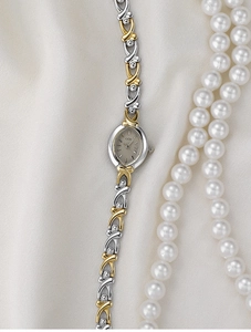 Detail of silver and gold vintage watch with X-shaped metal chain strap on silk background