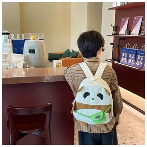 Detail showing the cartoon panda face and small green crossbody bag on the children backpack
