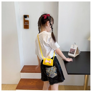 Detailed back view of a child wearing a mini yellow crossbody bag with a pink bow accent