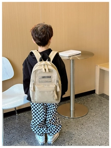 Enfant portant un sac à dos en toile beige avec étiquette FASHION en intérieur
