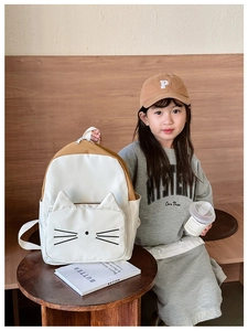 Detail view of cat-themed backpack showing 3D ears and embroidery on a young girl