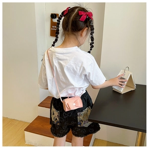 Pink mini crossbody bag for girls with a large bow detail shown on a child model