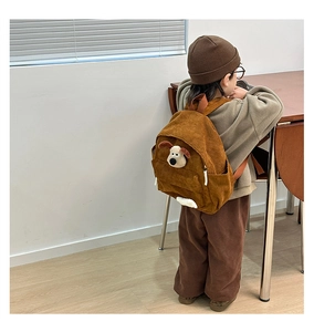 Close-up of brown corduroy kids backpack featuring a cute 3D cartoon dog character