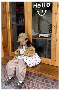 Outdoor shot of a girl wearing a yellow striped shirt and a quilted floral crossbody bag