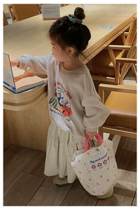Détail d'un sac à main blanc matelassé à fleurs avec une tenue beige pour enfant