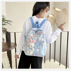 Vista laterale dello zaino a forma di coniglio blu con cuori indossato da un bambino a casa
