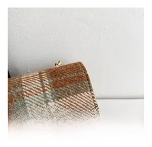 Macro shot of tweed plaid fabric texture with gold heart buckle and refined stitching