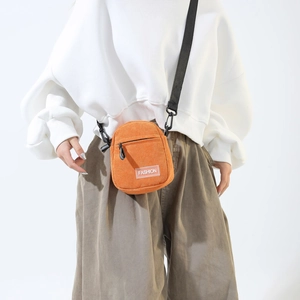 Mini sac bandoulière en velours côtelé orange avec étiquette Fashion sur un mannequin