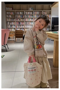 Sac beige matelassé pour filles avec broderies cerises dans un décor de bibliothèque